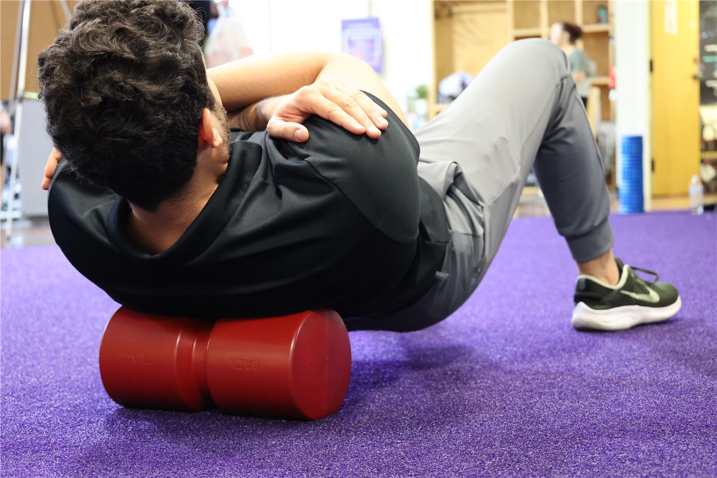 Person lying over a Back Trac foam roll to unload the spine